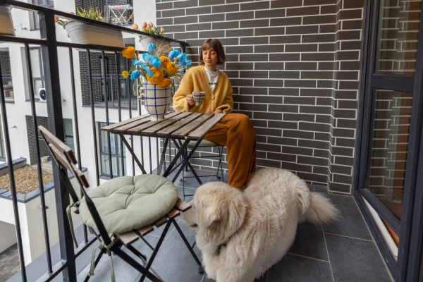 woman and pet dog sitting on apartment balcony